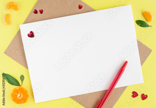 Minimalistic card mockup with envelope, postcard, pen, tangerines, slice of mandarin, red hearts on yellow background. Flat lay, top view, copy space. Valentines day, birthday concept.