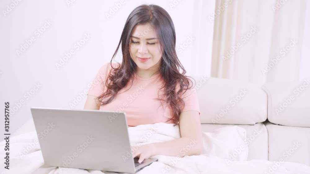 Beautiful young woman using a laptop computer while sitting on the sofa under blanket in the living room at home. Shot in 4k resolution Beautiful young woman using a laptop computer while sitting on the sofa under blanket in the living room at home. Shot in 4k resolution