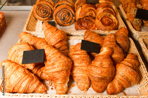 Delicious freshly baked pastries in a pastry shop. Many buns and croissants on a shelf of a baking shop