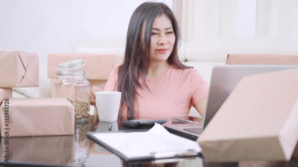 Female online shop owner working at home while eating snack and drinking coffee. Small Medium Enterprise or Start up concept. Shot in 4k resolution Female online shop owner working at home while eating snack and drinking coffee. Small Medium Enterprise or Start up concept. Shot in 4k resolution