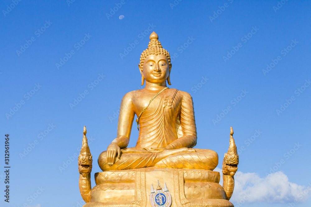 The golden Buddha made of 22 tons of brass and 12 meters high, inside the temple of popular and largest Bid Buddha in Chalong, Phuket, Thailand in the blue sky. Peace and meditation concept. The golden Buddha made of 22 tons of brass and 12 meters high, inside the temple of popular and largest Bid Buddha in Chalong, Phuket, Thailand in the blue sky. Peace and meditation concept.