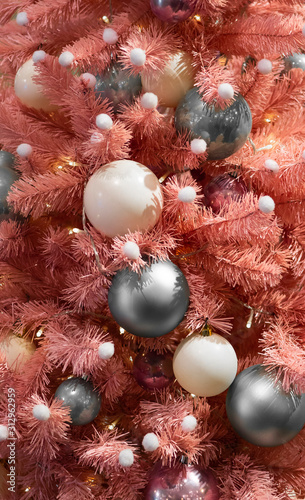 Pink Christmas tree.Pink Xmas tree.A creative, festive Christmas tree stands in the building, lush branches are decorated with white and gray plastic balls,and small garlands that illuminate the tree.