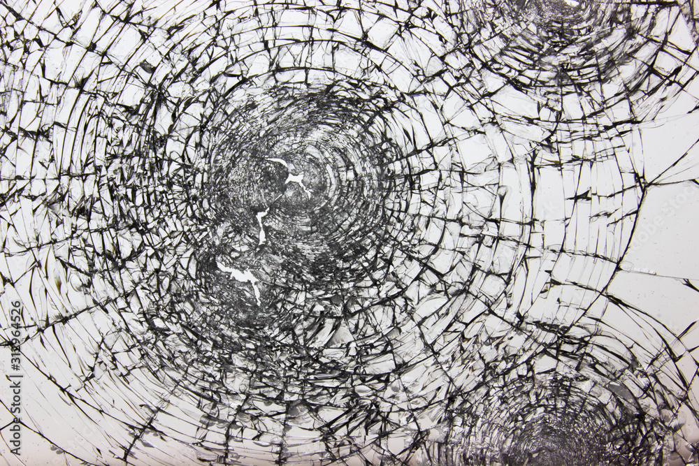 Obraz premium Cracks on broken glass after gun shots. Vandalism and assault with a firearm. Damaged window robbers.