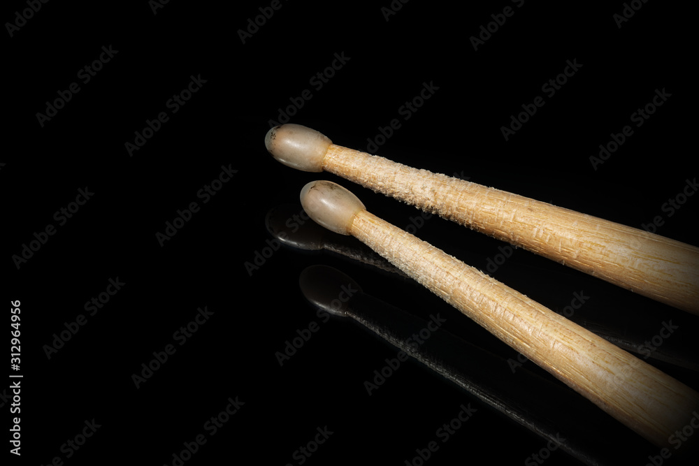 Close-up of a pair of used wooden drumsticks on a black background with reflections and copy space. Percussion instrument Close-up of a pair of used wooden drumsticks on a black background with reflections and copy space. Percussion instrument