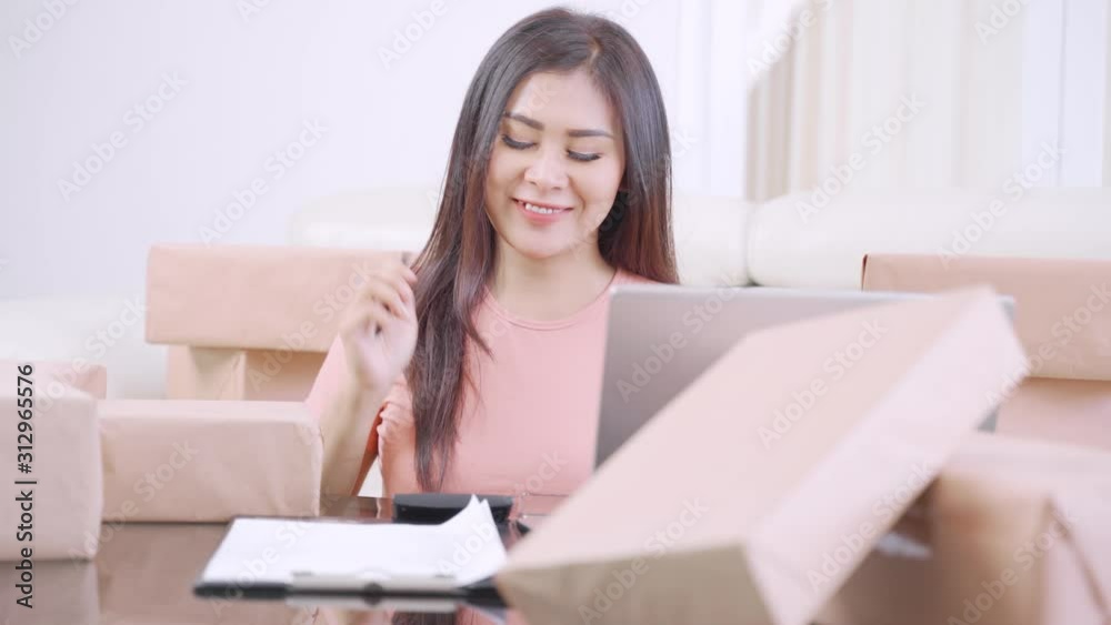 Pretty woman online shop owner working with calculator and cardboard at home. Small Medium Enterprise or Start Up concept. Shot in 4k resolution Pretty woman online shop owner working with calculator and cardboard at home. Small Medium Enterprise or Start Up concept. Shot in 4k resolution
