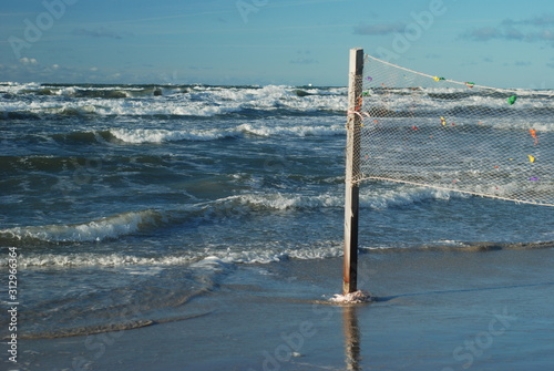 Big waves in the stormy sea, the old volleyball net on the beach