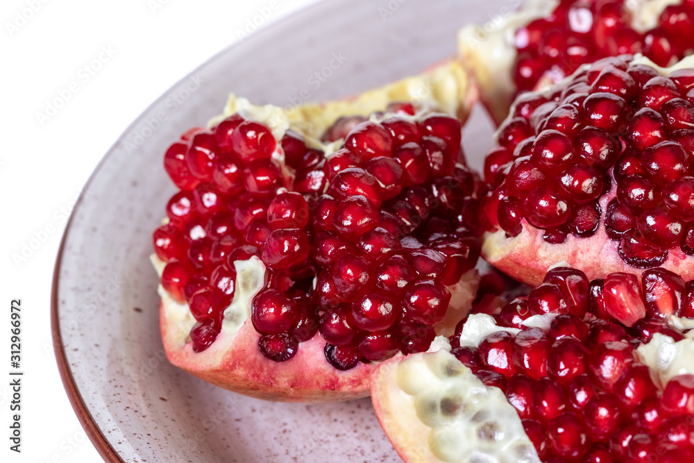 Ripe pomegranate on a plate isolated on white background. Ripe pomegranate on a plate isolated on white background.