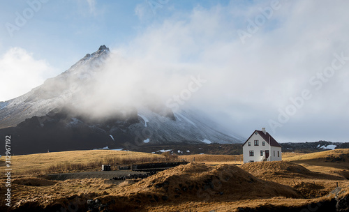 Lonely  house at the small fishing village of Arnarstapi and mountain cliff covered in snow  at Snæfellsnes peninsula in Iceland photo
