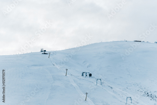 scenic view of snowy mountain with gondola lift and white fluffy clouds above