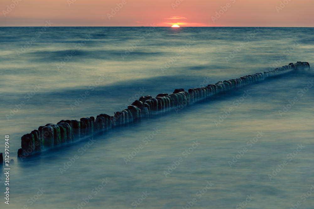 Naklejka premium Wooden breakwater at sunset on the Baltic Sea