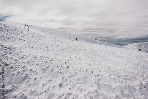 scenic view of snowy mountains with gondola lift and white fluffy clouds