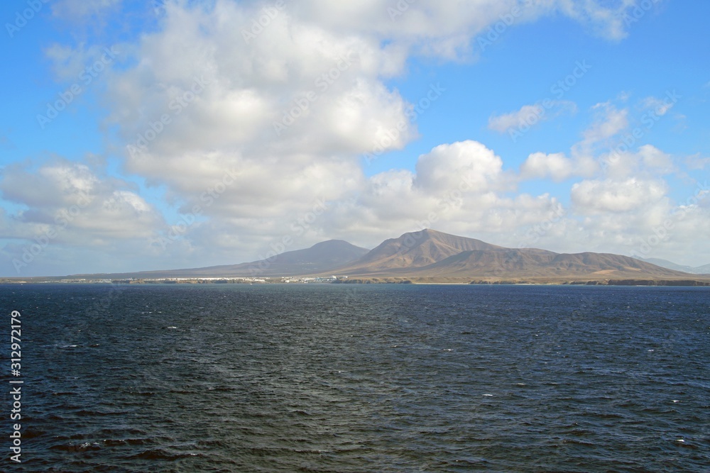 View from the Atlantic Ocean to the Canary Islands. Blue sky and skyline. White clouds and mountains