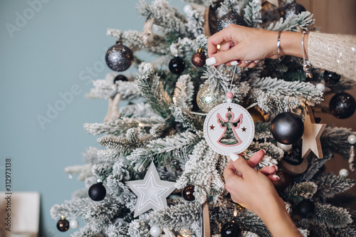 Cropped phoro of lady hands holding beautiful deer toy near the Christmas tree. New Year eve concept photo