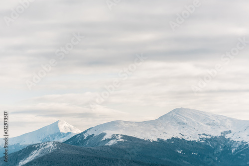 Scenic view of snowy mountains in white fluffy clouds