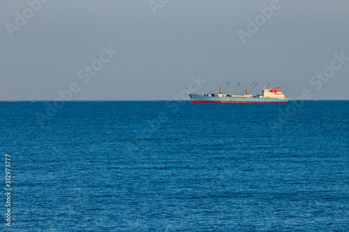 freight ship sailing on the horizon