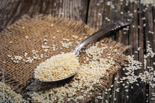 sesame seeds in spoon on wooden background