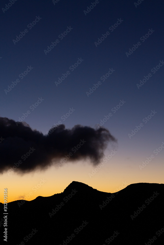 Mountain silhouette with clouds at sunrise time.