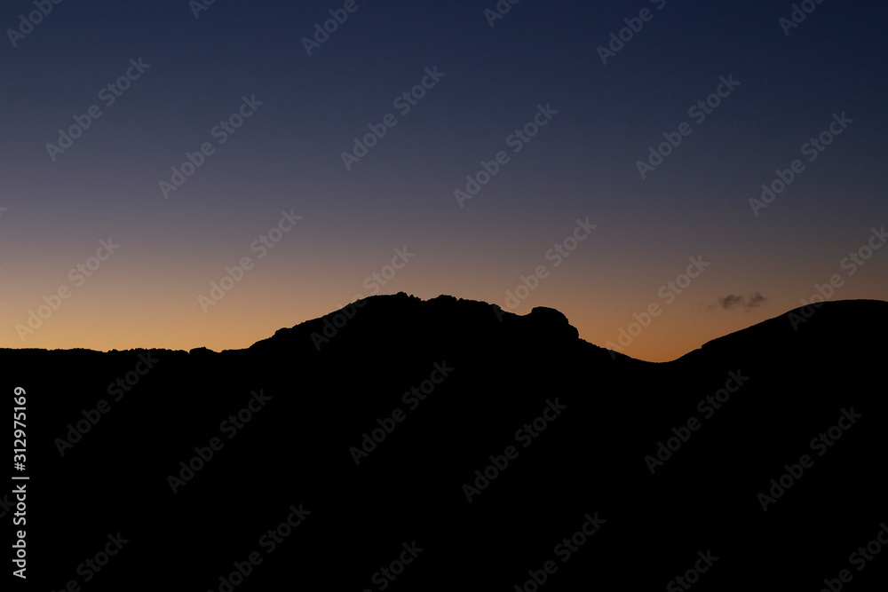 Mountain silhouette with clouds at sunrise time.