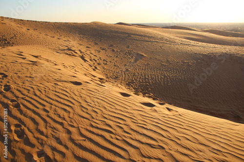 sand dunes in the desert with snadows in the evening with foot steps