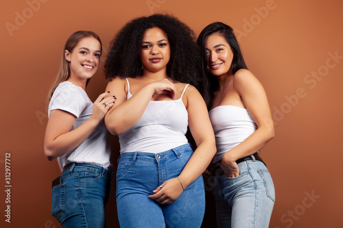 young pretty asian, caucasian, afro woman posing cheerful together on brown background, lifestyle diverse nationality people concept