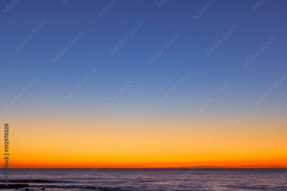 Orange-blue serene sky over the sea at sunset
