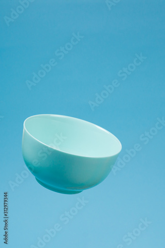 A blue ceramic mattle deep bowl for breakfast flying on blue background. photo