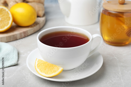Fresh tea with honey and lemon on light grey marble table, closeup