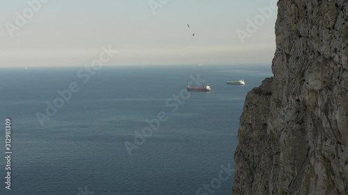 Two oil tankers sail in the distance in Gibraltar's bay. There is a part of Gibraltar's rock visible.