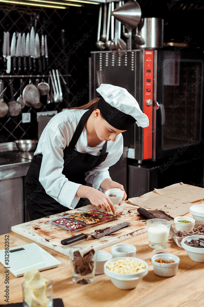attractive chocolatier in apron looking at dark chocolate bars attractive chocolatier in apron looking at dark chocolate bars