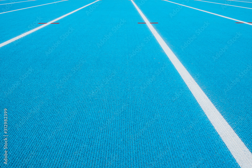 Sport background. Blue running track with white lines and red mark in sport stadium. Top view