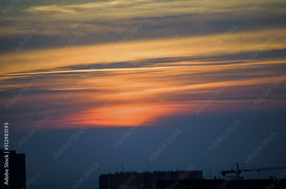 red clouds over the city of the ending day illuminated by the setting sun