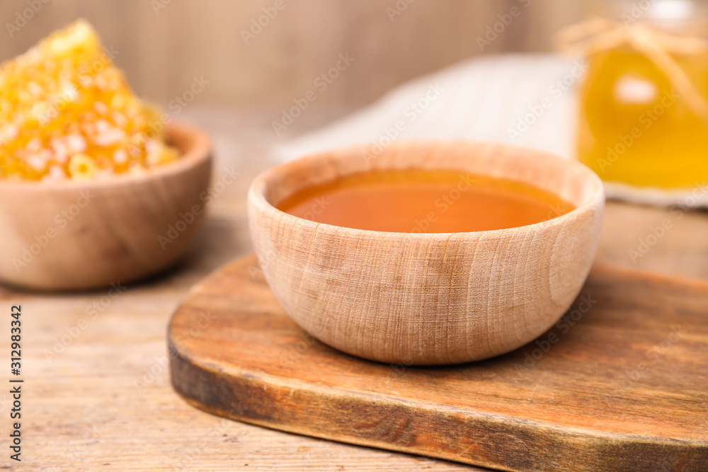 Tasty aromatic honey in bowl on wooden table Tasty aromatic honey in bowl on wooden table