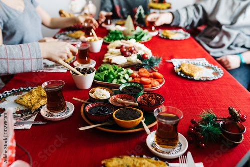 a group of friends are having a breakfast at christmas morning. New Year Breakfast at home. Homemade Breakfast with family with red background. Holding tea and serving breakfast . Traditional Turkish 