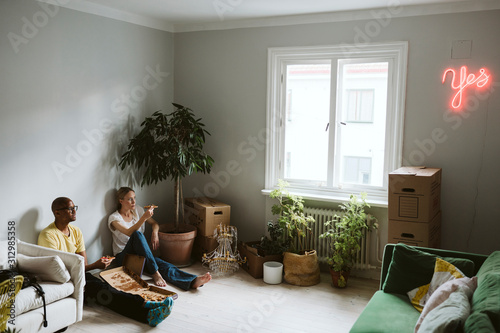 Couple sitting on floor and having pizza photo