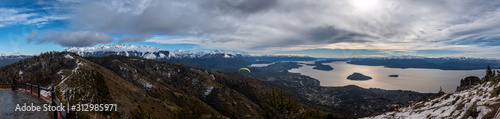 Panoramic view of landscape and paragliding over Nahuel Huapi lake and mountains, with snowed peaks in the background. Concept of freedom, adventure