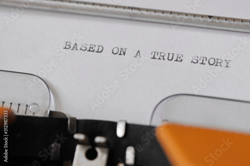 Close up footage of ˝BASED ON A TRUE STORY˝ written on a paper, on an old typewriter with capital letters...