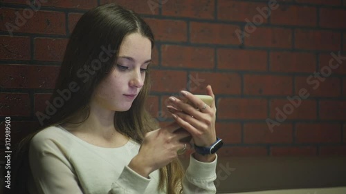 Teenager with problem skin. Young cute caucasian girl surfing in a smartphone. Close up.