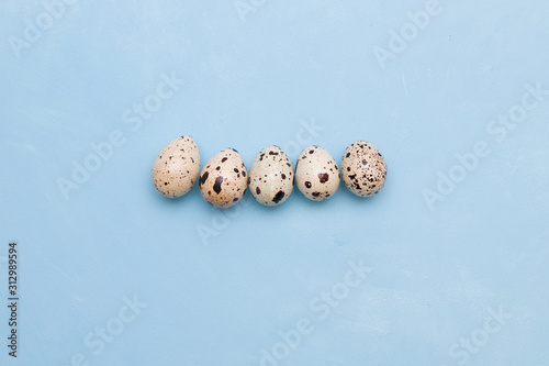 five quail eggs on a blue background pattern place copy top view for your text
