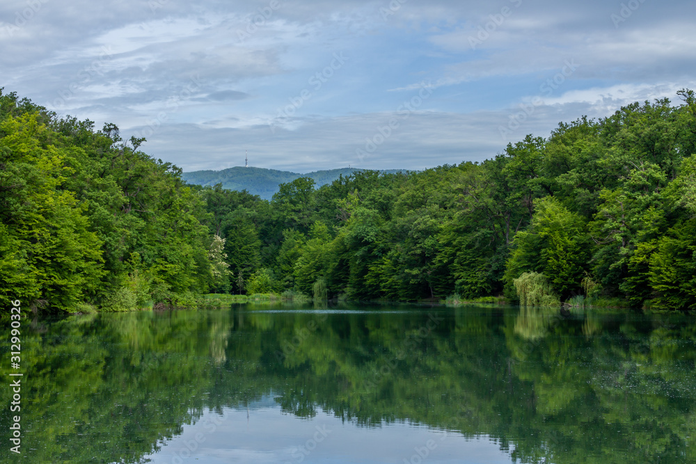 Lake in Maksimir park with green tree reflections and a mountain Medvednica in Zagreb