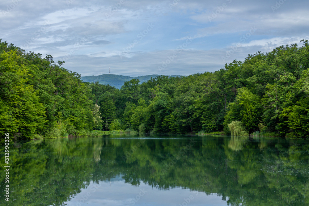 Lake in Maksimir park with green tree reflections and a mountain Medvednica in Zagreb Lake in Maksimir park with green tree reflections and a mountain Medvednica in Zagreb