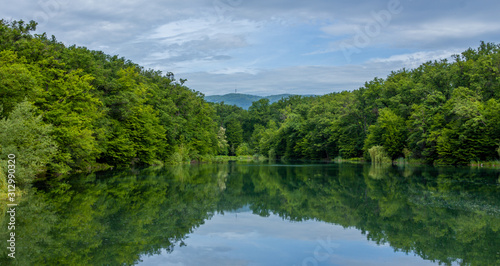 Panorama of a lake in Maksimir park with green tree reflections and a mountain Medvednica in Zagreb