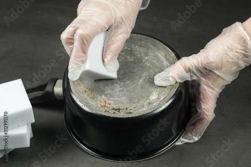 Obraz na płótnie Hands in gloves cleaning old pot with eco friendly magic sponge, no detergent house cleaning w salonie