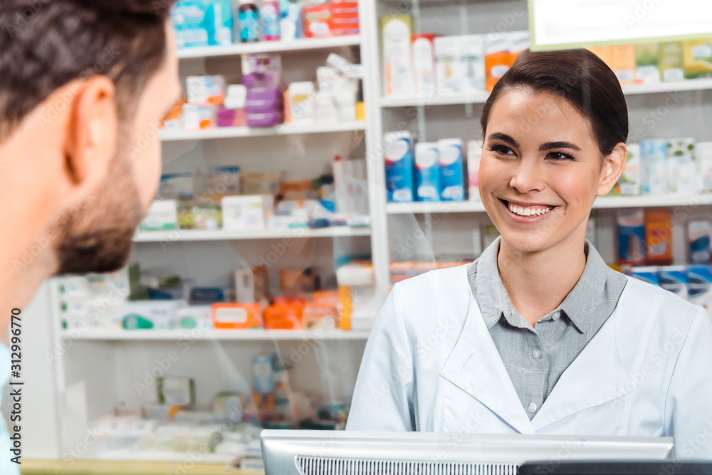 Selective focus of druggist smiling to customer at pharmacy counter
