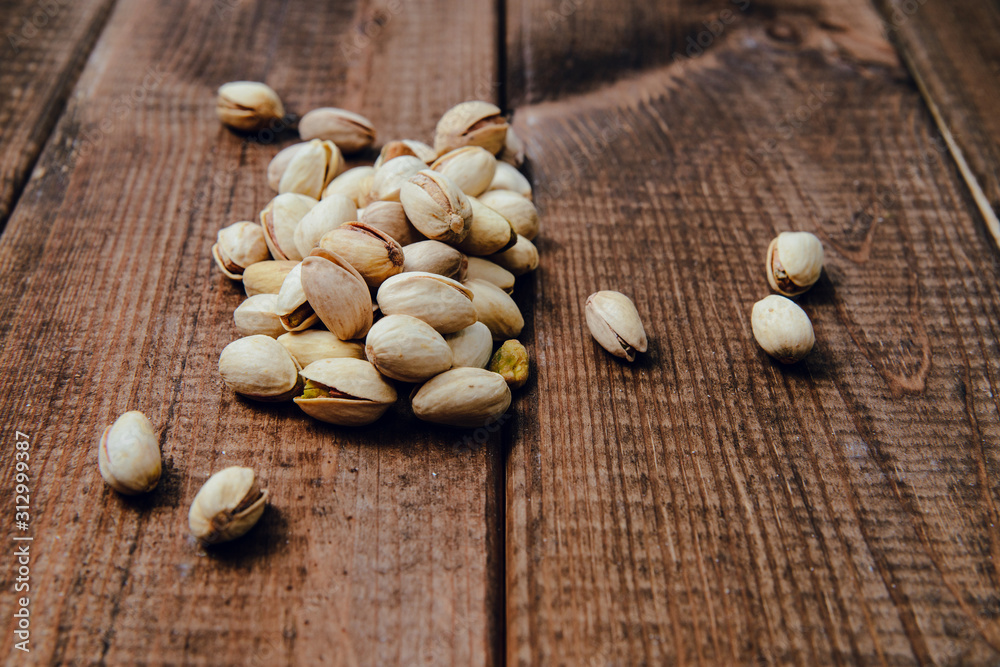 Nuts pistachios on a wooden background. The concept of eating nuts, giving them to a meal. Nuts pistachios on a wooden background. The concept of eating nuts, giving them to a meal.
