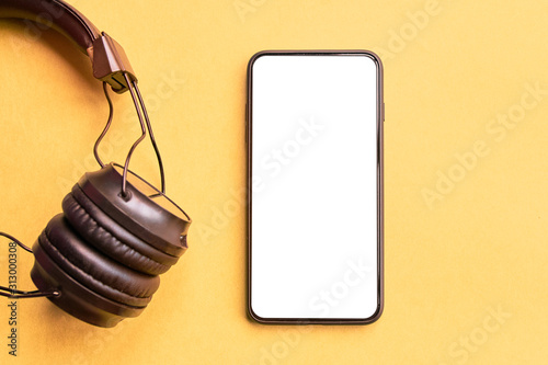 Wireless Headphones and smartphone on colorful background. Isolated Phone and earphones for music sound on yellow background.