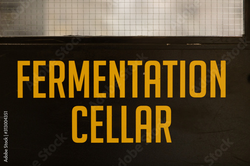 fermentation cellar yellow vinyl sticker text Information sign on a black door, industrial room symbol, selective focus and close up view photo