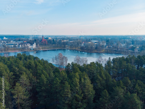 Aerial beautiful panoramic image of Druskininkai cityscape over Druskonis lake during early spring daytime.