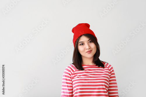 Portrait of beautiful young Asian woman on light background