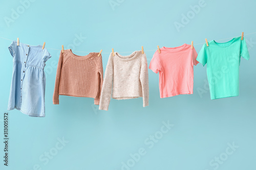 Clean laundry hanging on line against color background