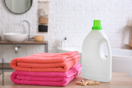 Clean laundry and washing liquid on table in bathroom